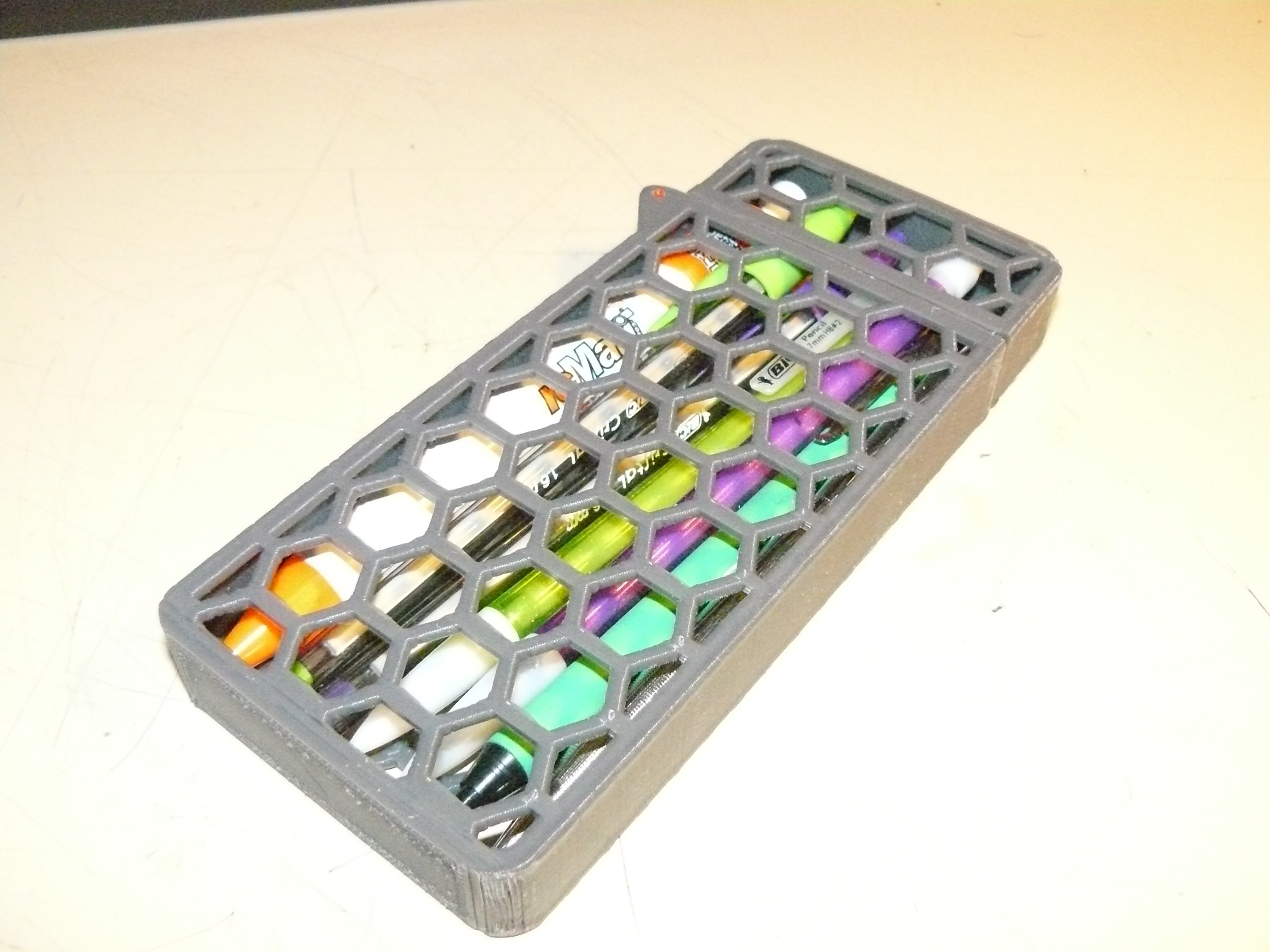 Hexagonal mesh hinged writing implement vessel